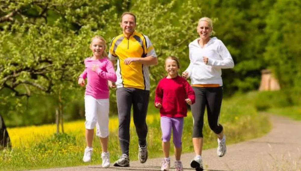 Afiche de la correcaminata: una familia corre por un camino arbolado