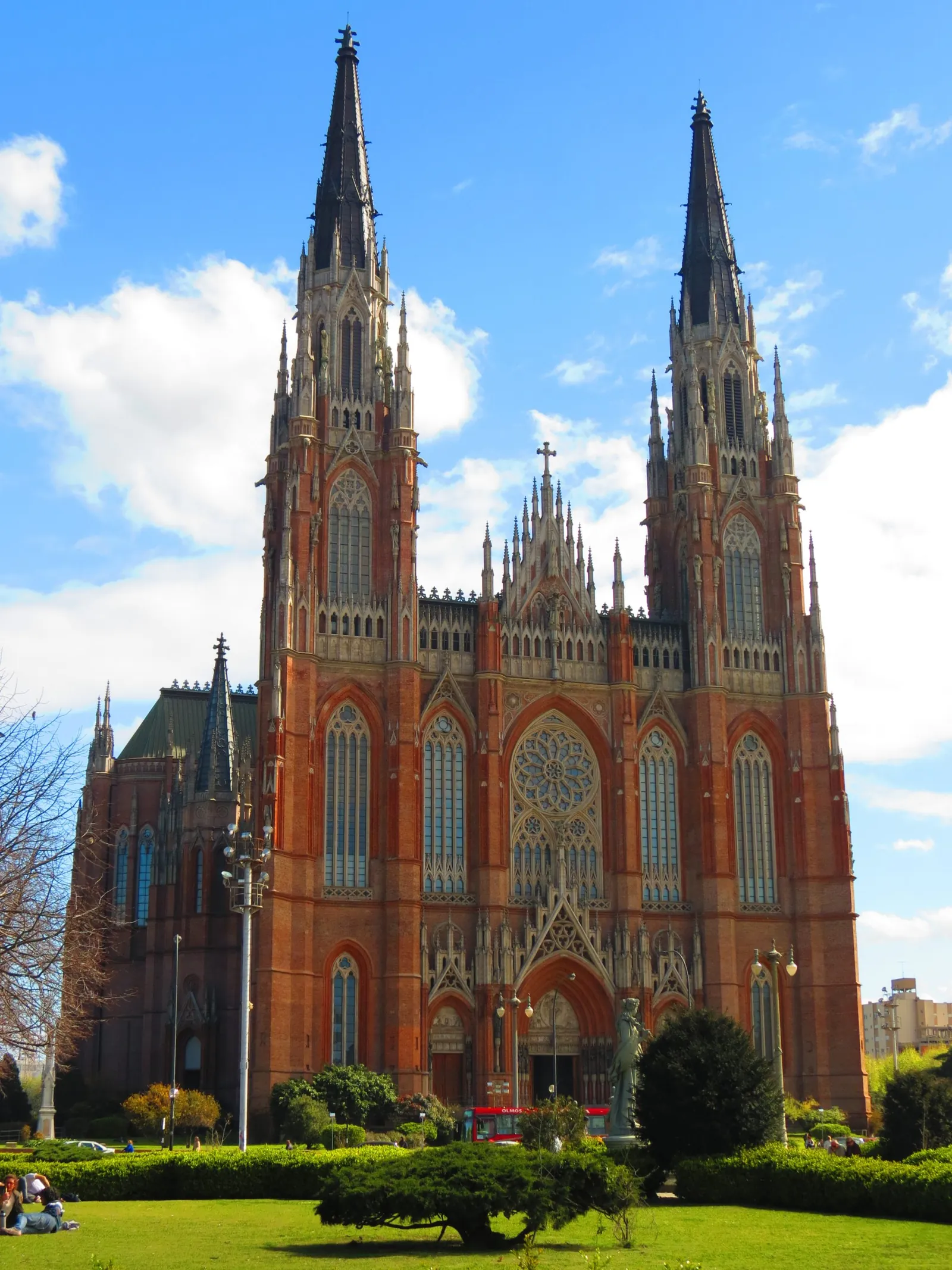 Frente de la Catedral de La Plata, de ladrillo rojo y dos torres góticas, vista desde los jardines de Plaza Moreno