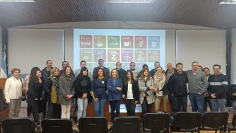 Grupo de participantes posa en un auditorio frente a una pantalla con los Objetivos de Desarrollo Sostenible.