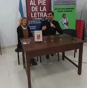 Presentación del ciclo Al pie de la letra: dos personas hablan detrás de una mesa con el afiche del programa de fondo.