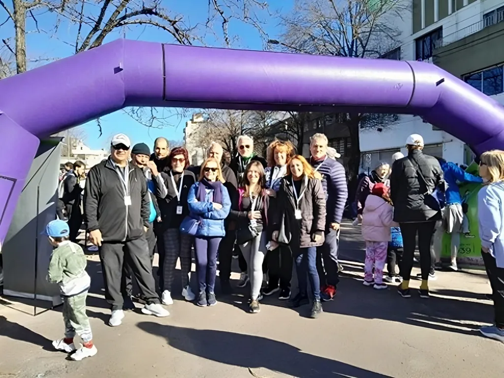 Participantes y organizadores posan bajo el arco inflable de largada de una correcaminata.