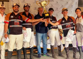 Un equipo de polo levanta el trofeo junto a dirigentes en la entrega de premios.