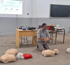 Un instructor prepara los muñecos de práctica antes de un taller de RCP en un aula.