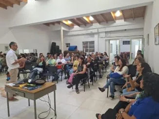 Auditorio lleno sigue la charla de un instructor durante una jornada de salud.