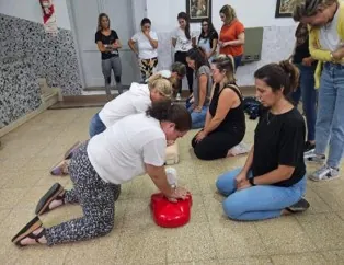 Un grupo de mujeres practica reanimación sobre un muñeco con un desfibrilador de entrenamiento.