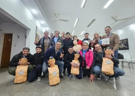 Los participantes de un taller de RCP posan con los muñecos de práctica al finalizar.